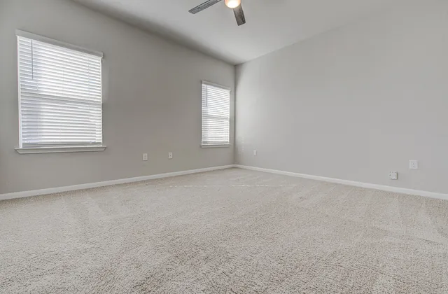 an empty room with ceiling fan and window