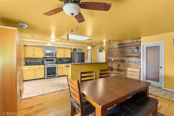 a kitchen with stainless steel appliances kitchen island granite countertop a refrigerator a stove and a dining table with wooden floor