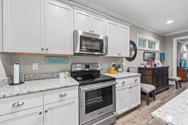 a kitchen with granite countertop white cabinets and stainless steel appliances
