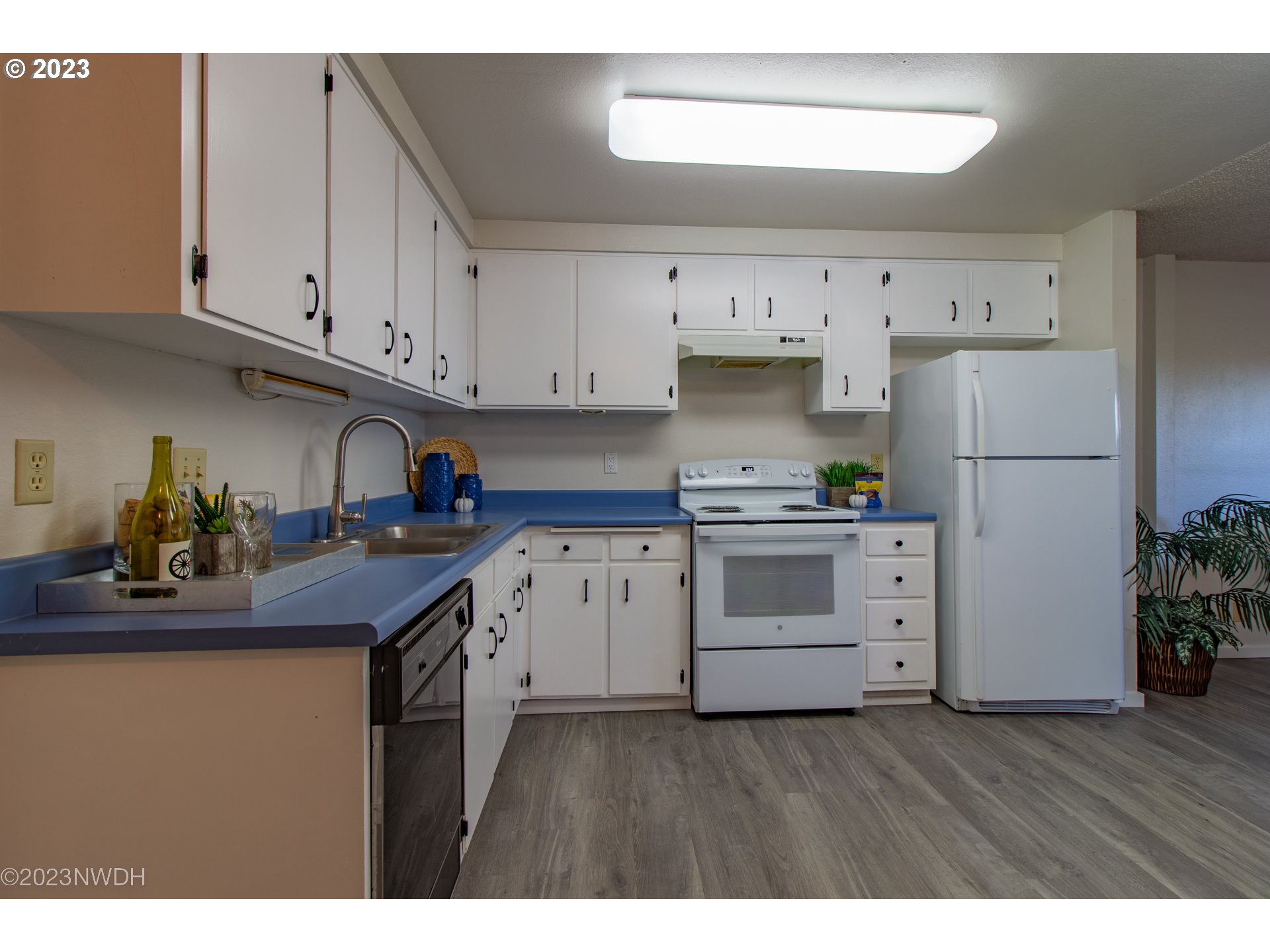 1302 Quaker Street Eugene, OR 97402 - Photo 14 of 28 a kitchen with granite countertop a white refrigerator oven a sink dishwasher and white cabinets with wooden floor