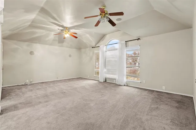 an empty room with chandelier fan and windows