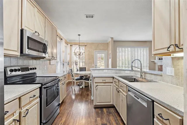 a kitchen with granite countertop a sink a counter space appliances and cabinets
