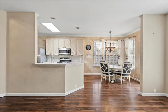 a kitchen with stainless steel appliances granite countertop a stove top oven a sink and white cabinets with wooden floor