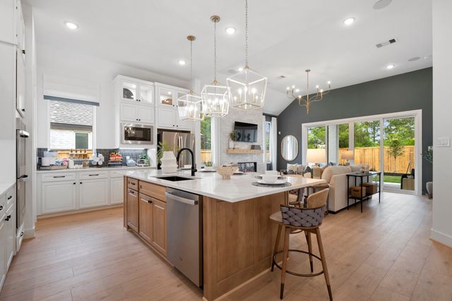 a kitchen with stainless steel appliances granite countertop a stove top oven a sink dishwasher and white cabinets with wooden floor