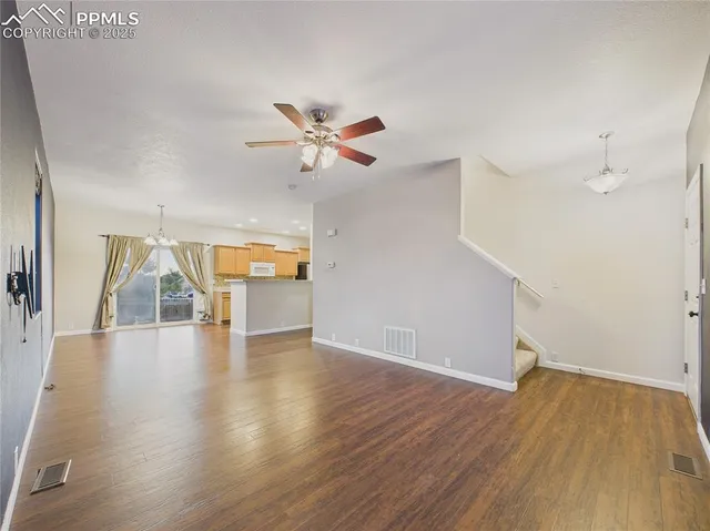 an empty room with wooden floor and ceiling fan