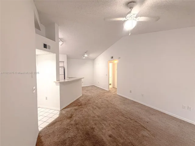 an empty room with a kitchen and a ceiling fan
