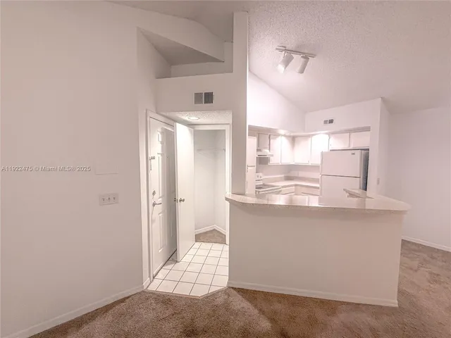 a view of a kitchen with kitchen island a sink wooden floor and a refrigerator
