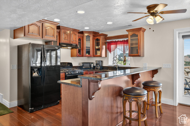 4768 East Hickman Canyon Road Stockton, UT 84071 - Photo 42 of 85 Kitchen featuring black appliances, cabinets, wood style floors and a bar.