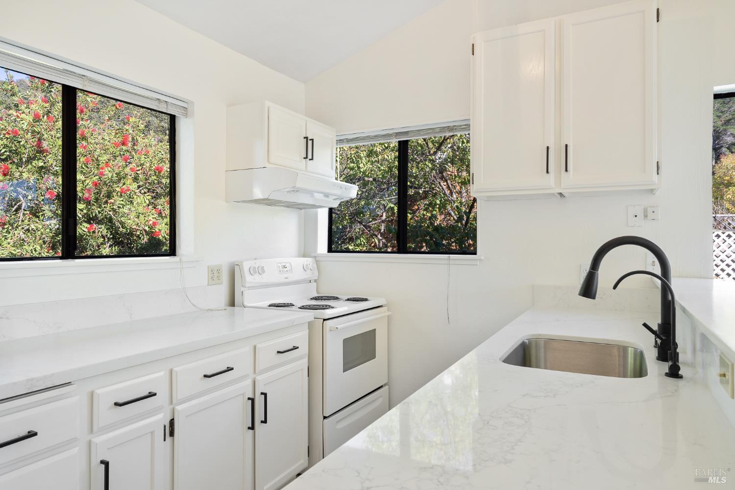 a kitchen with white cabinets a sink and a window