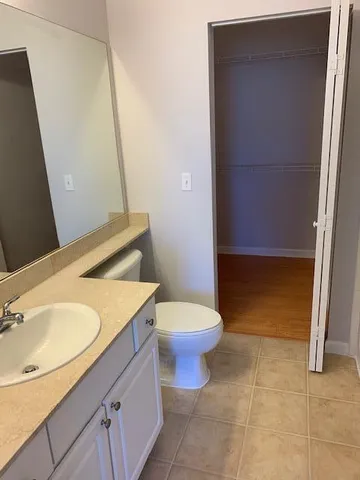 a bathroom with a granite countertop toilet sink and mirror