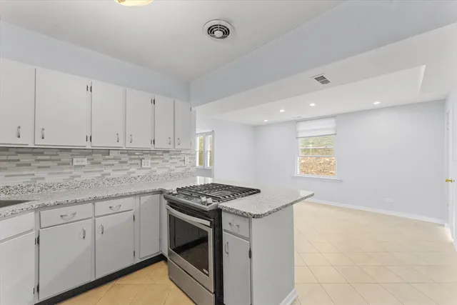 a kitchen with granite countertop white cabinets stainless steel appliances and a counter space