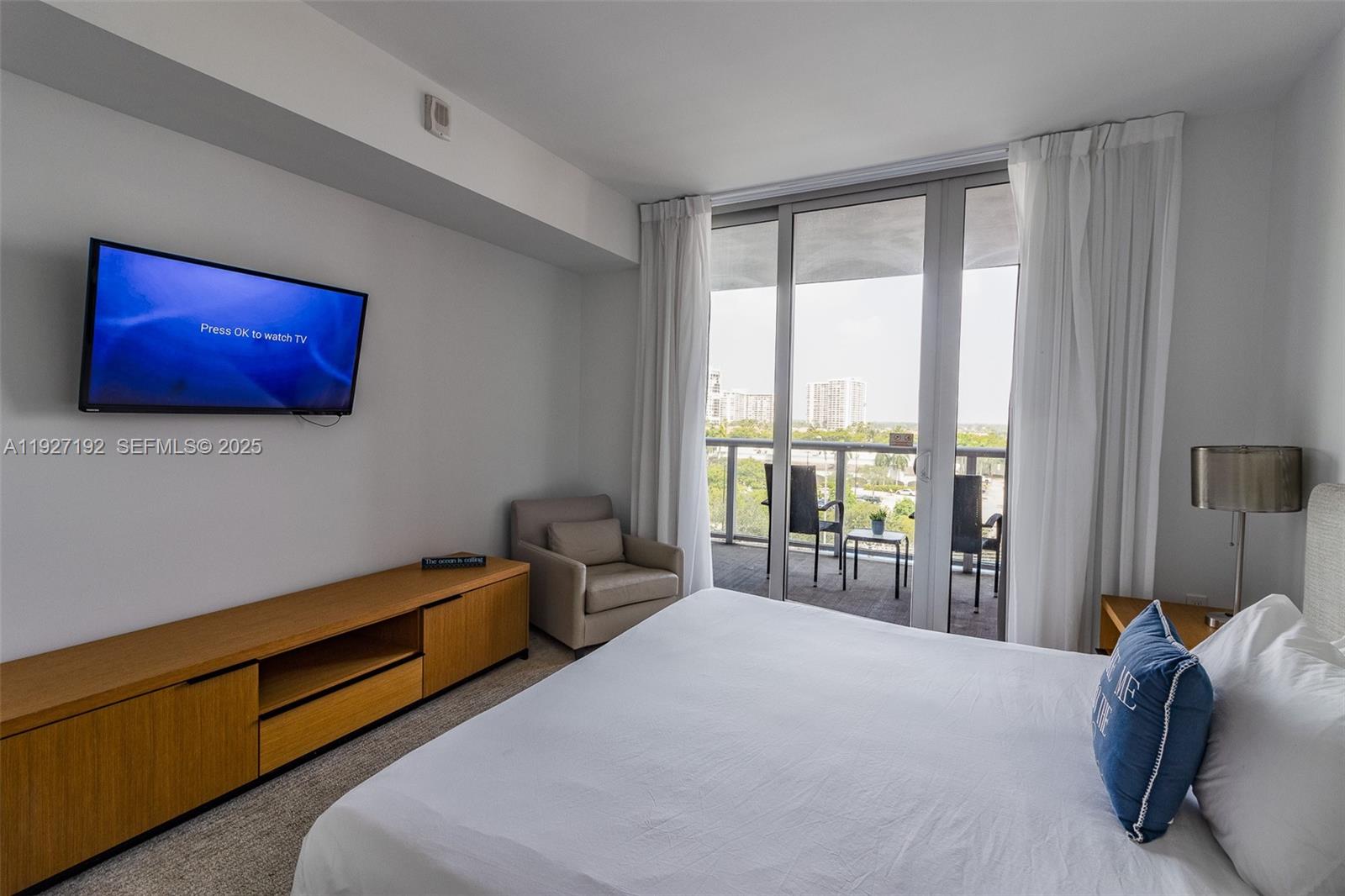 2602 East Hallandale Beach Boulevard, Unit R708 Hallandale Beach, FL 33009 - Photo 15 of 42 a bedroom with a bed and glass window