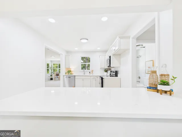 a kitchen with stainless steel appliances granite countertop a stove top oven a sink a refrigerator with white cabinets and wooden floor