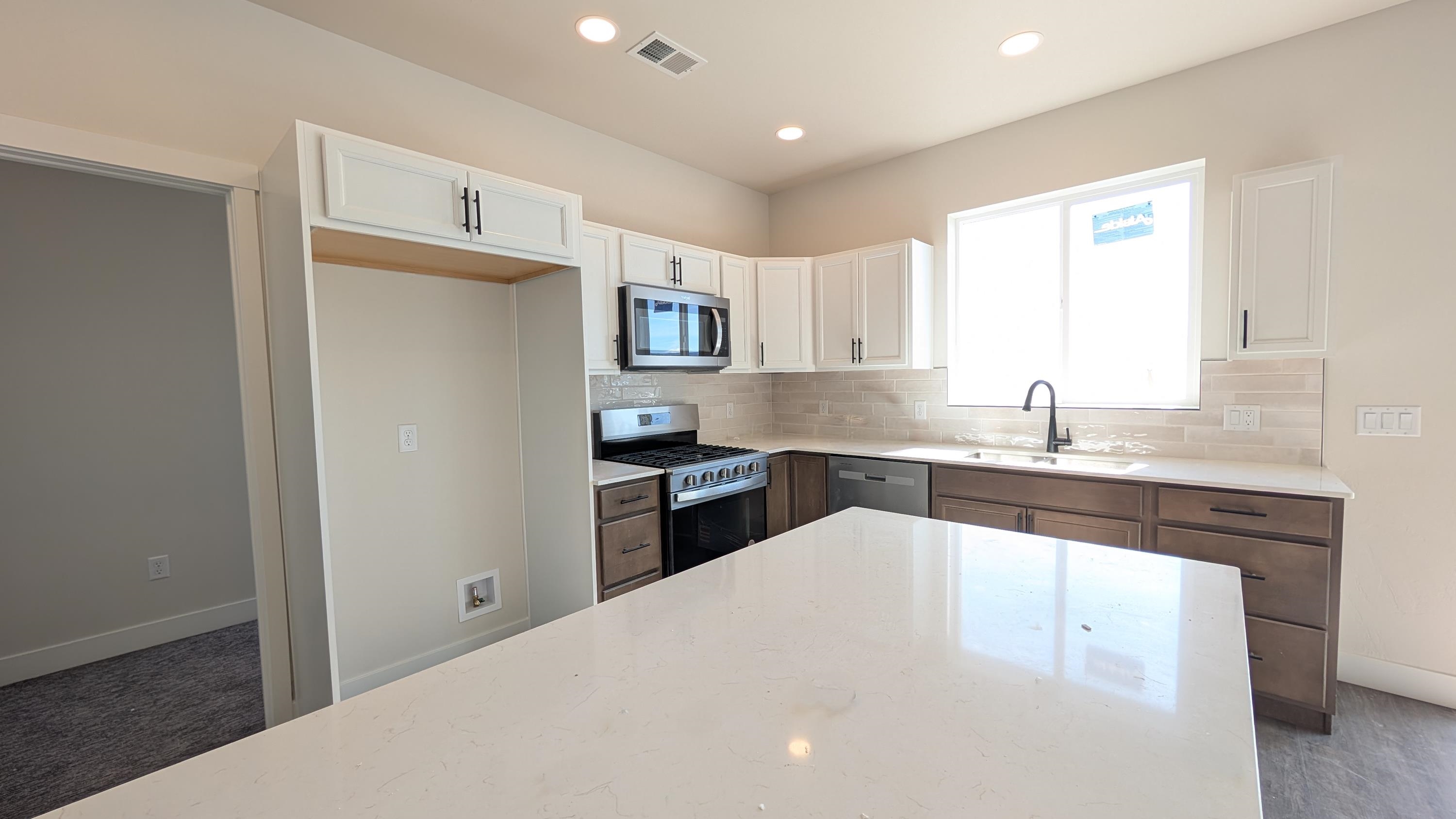 2463 Revere Road, Unit A Grand Junction, CO 81505 - Photo 5 of 13 a kitchen with kitchen island a sink stainless steel appliances and white cabinets