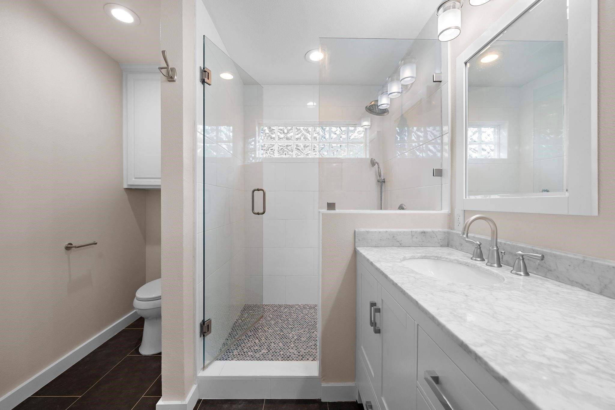 954 West 41st Street Houston, TX 77018 - Photo 14 of 19 a bathroom with a granite countertop sink a toilet a mirror and shower