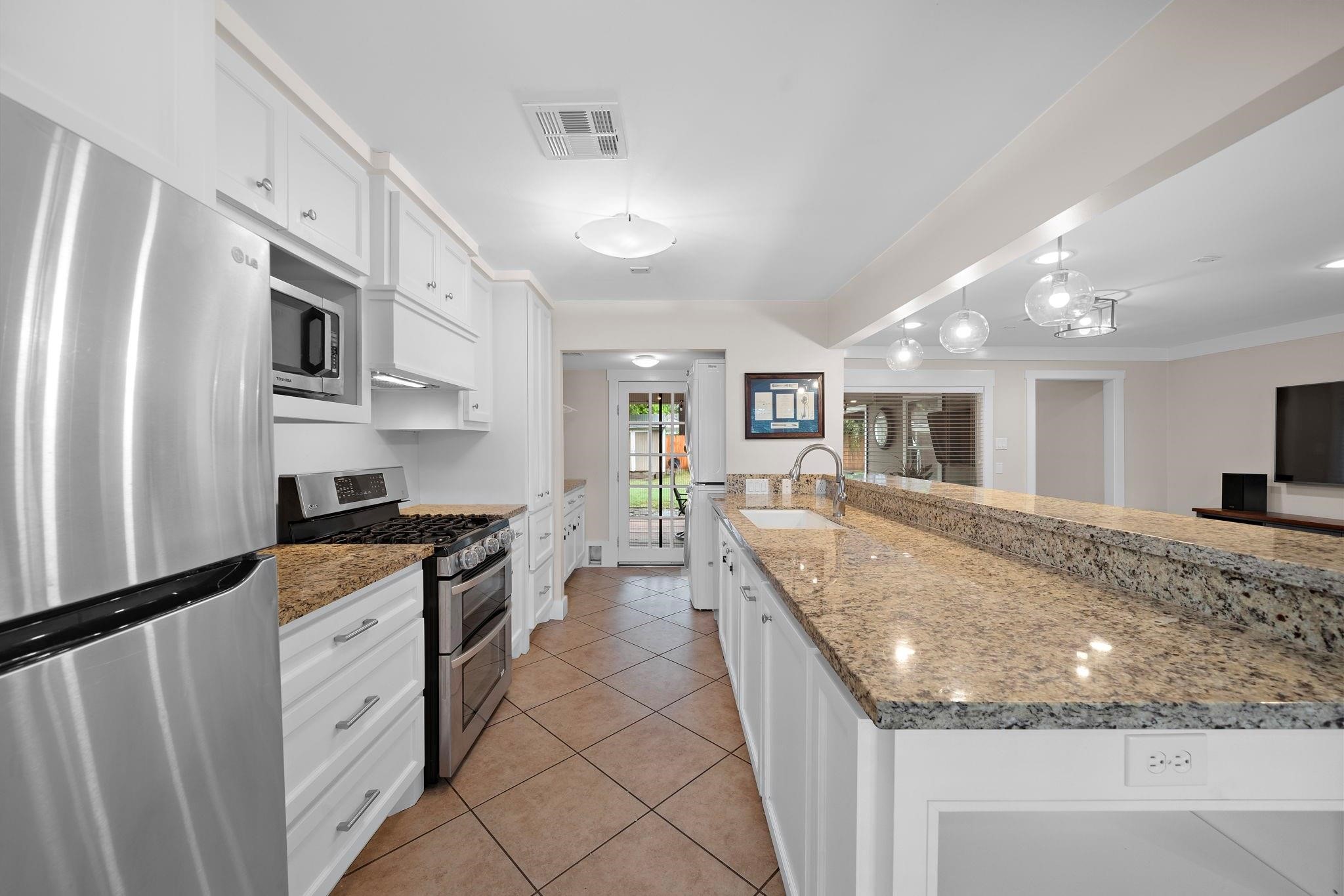 954 West 41st Street Houston, TX 77018 - Photo 10 of 19 a large kitchen with kitchen island a stove a sink a refrigerator and white cabinets with wooden floor