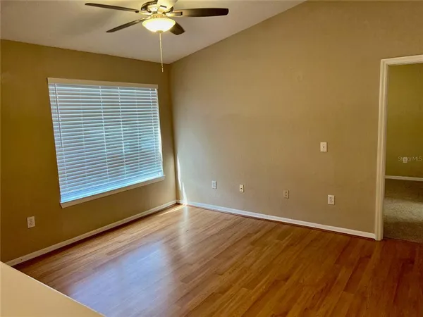 a view of an empty room with window and wooden floor