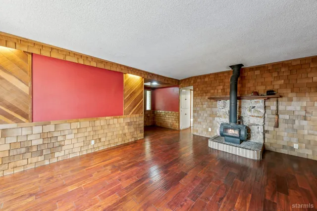 a view of an empty room with wooden floor and windows