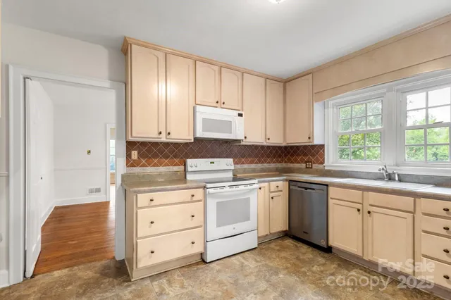 a kitchen with white cabinets sink and window