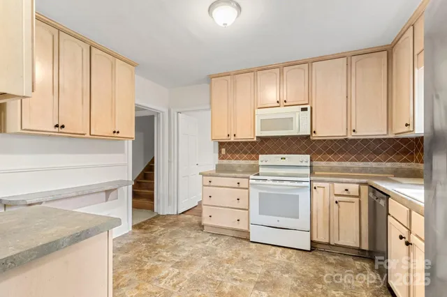 a kitchen with granite countertop white cabinets and white appliances
