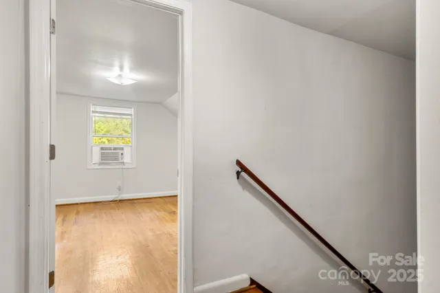a view of an empty room with wooden floor and closet