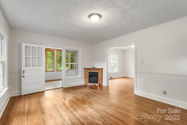 an empty room with wooden floor fireplace and windows