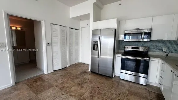 a kitchen with stainless steel appliances kitchen island granite countertop a refrigerator and a stove top oven