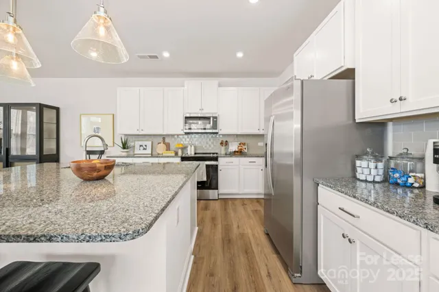 a kitchen with stainless steel appliances granite countertop a refrigerator a stove and a sink