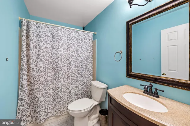 a bathroom with a granite countertop sink toilet and a mirror