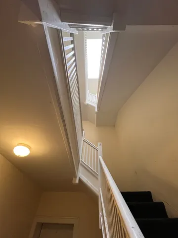 a view of stairs and an empty room with wooden floor