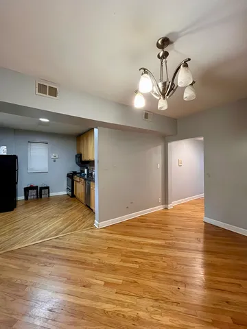 a view of an empty room with kitchen and chandelier