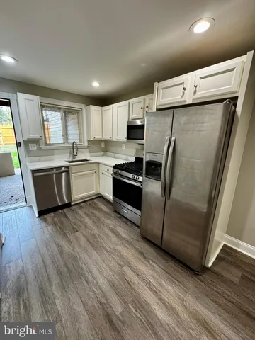 a kitchen with granite countertop a refrigerator a sink a stove a microwave a counter top space and cabinets