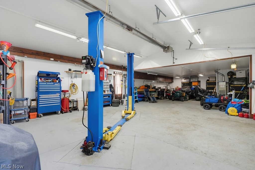 23055 Snell Road Columbia Station, OH 44028 - Photo 48 of 50 Spacious garage featuring a vehicle lift, concrete flooring, overhead fluorescent lighting, exposed wood beams, and a dedicated workspace