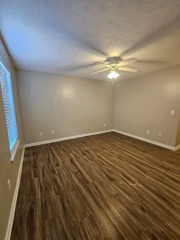 en empty room with wooden floor and fan