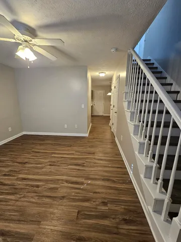 a view of an empty room with wooden floor and staircase