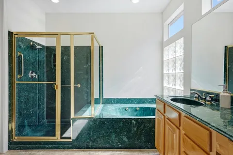 a bathroom with a granite countertop sink a mirror and shower