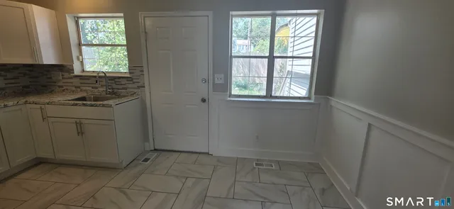 a view of a kitchen with white cabinets and a window