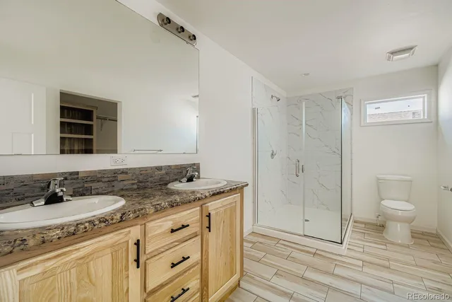 a spacious bathroom with a granite countertop sink a toilet and a shower