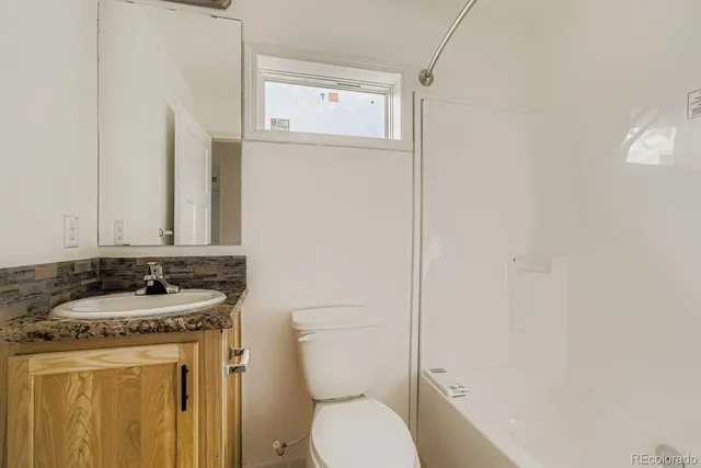 a bathroom with a granite countertop sink toilet and mirror