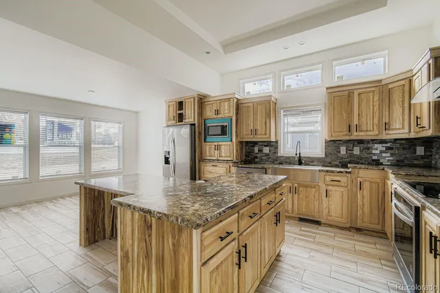 a kitchen with stainless steel appliances granite countertop a stove a sink and a refrigerator
