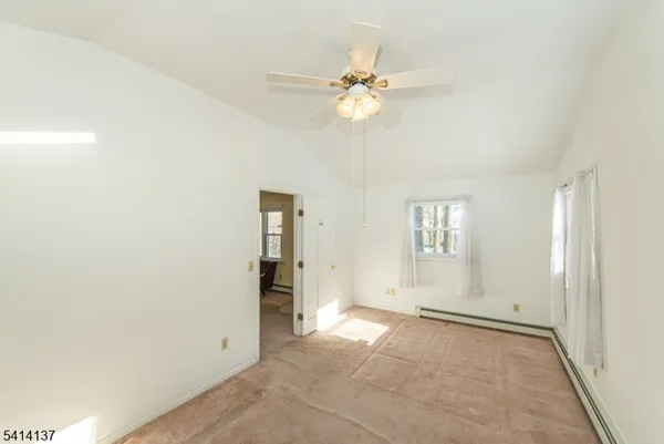 an empty room with chandelier fan and windows