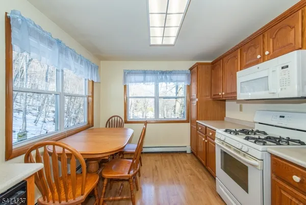 a kitchen with stainless steel appliances granite countertop a stove top oven a sink a dining table and chairs with wooden floor