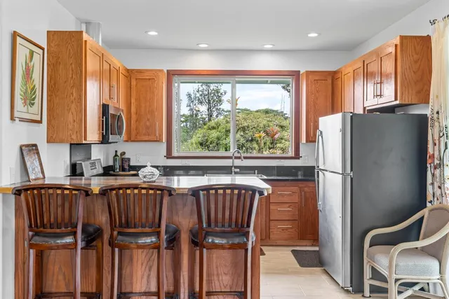 a kitchen with stainless steel appliances granite countertop a refrigerator a sink dishwasher and wooden cabinets