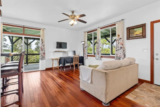 a living room with furniture large window and wooden floor