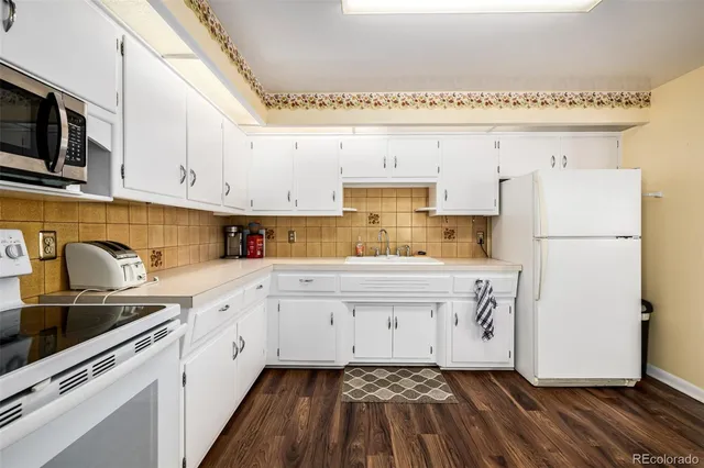 a kitchen with granite countertop white cabinets and refrigerator
