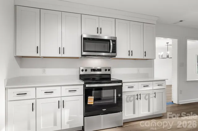 a kitchen with granite countertop white cabinets and white appliances