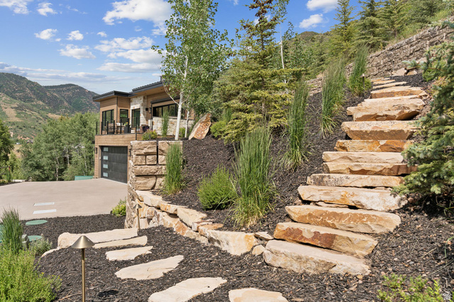 1400 Weber Wild Road Oakley, UT 84055 - Photo 44 of 55 Terraced landscaping featuring natural stone steps and retaining walls, complemented by varied evergreen and deciduous plantings