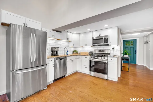 a kitchen with stainless steel appliances granite countertop a stove a sink and a microwave