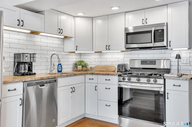 a kitchen with stainless steel appliances a refrigerator a stove top oven a sink and cabinets
