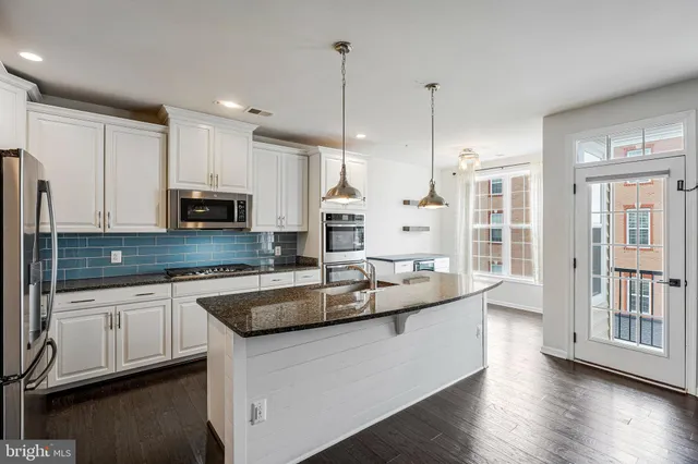 a large kitchen with stainless steel appliances granite countertop a sink a stove and a wooden floors